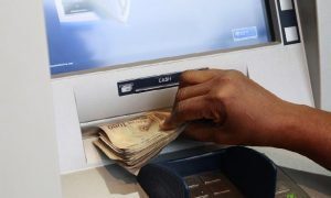 A woman takes Nigerian Naira from a bank’s automated teller machine (ATM) in Ikeja district in the commercial capital Lagos