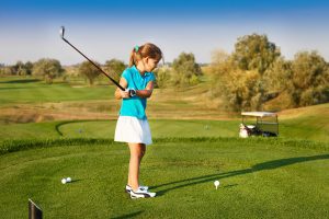 Cute little girl playing golf on a field outdoor