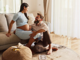 Happy expecting couple talking at home.